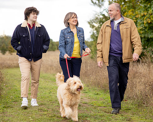 Andrea, her husband Chris, their daughter Amelia, and Cooper, the lovable labradoodle walking together